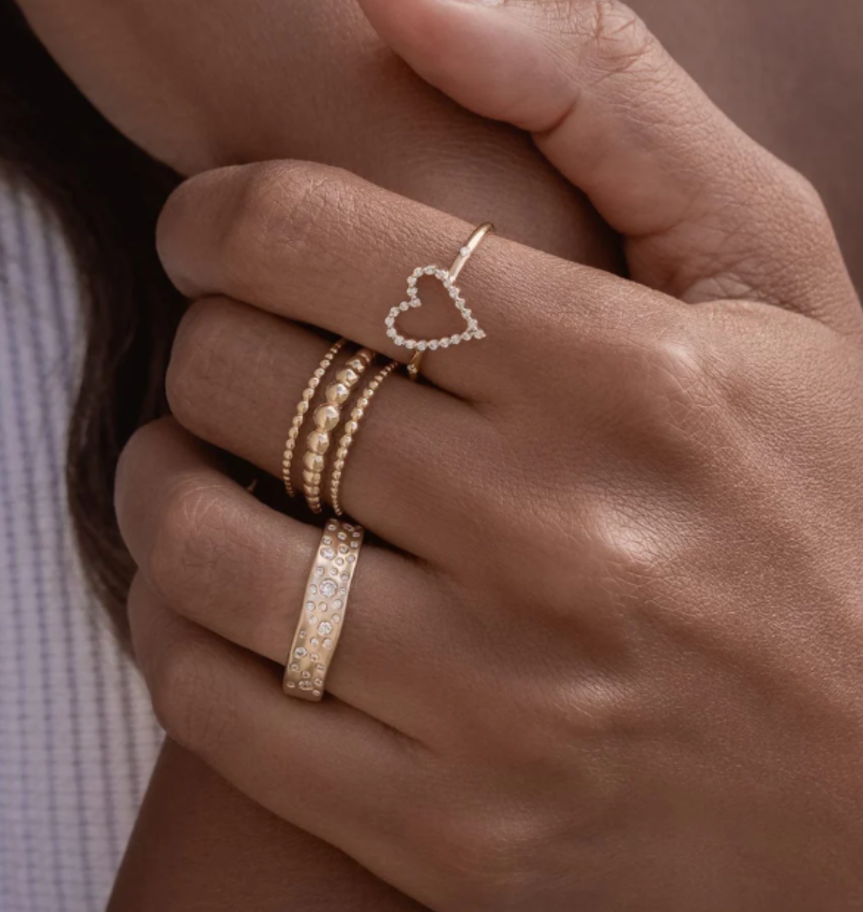 Close-up of a hand wearing gold rings with heart design