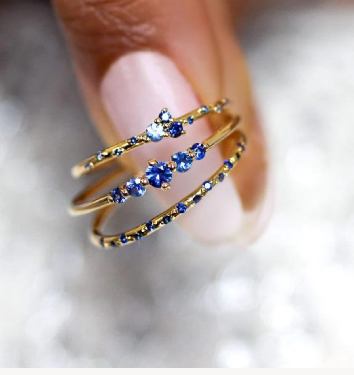 Gold and blue beaded ring on a finger with a blurred background